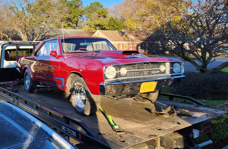 A red 1967 Dodge Dart strapped down on Royce's black flatbed in low evening sun, MC 751299 lettered on the rail