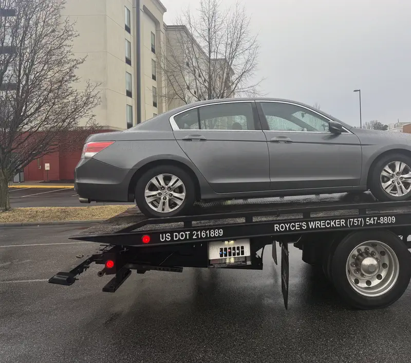 A grey sedan on Royce's flatbed, the rail lettered US DOT 2161889 and Royce's Wrecker (757) 547-8809