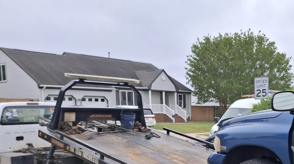Royce's flatbed tilted down beside a blue Dodge Ram pickup, US DOT 2161889 lettered on the bed